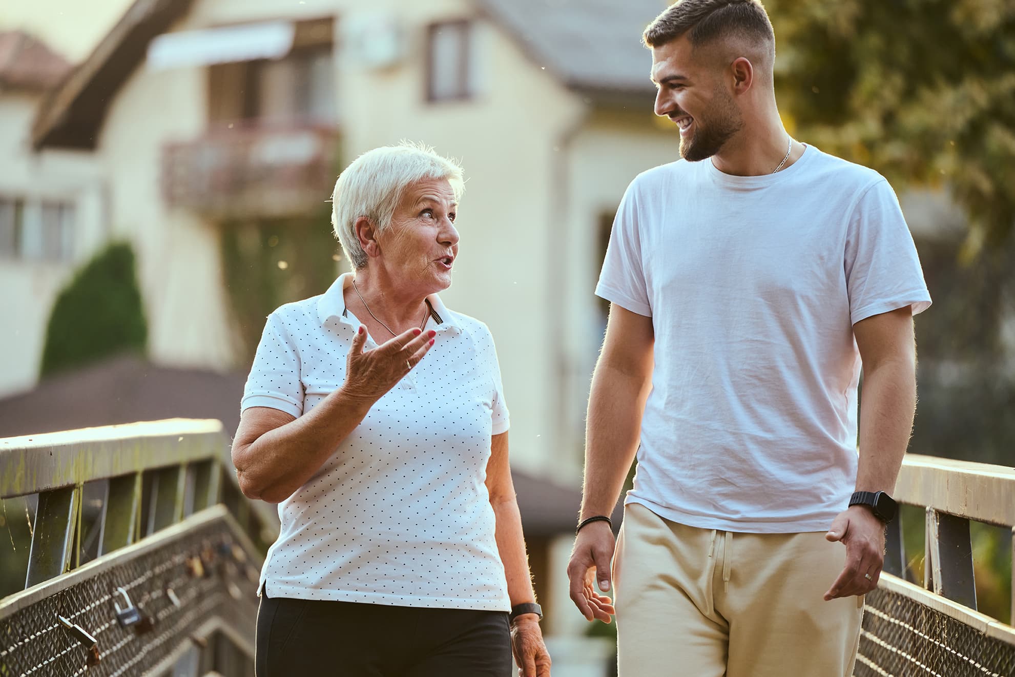 Two neighbors sharing a walk across a bridge at sunset